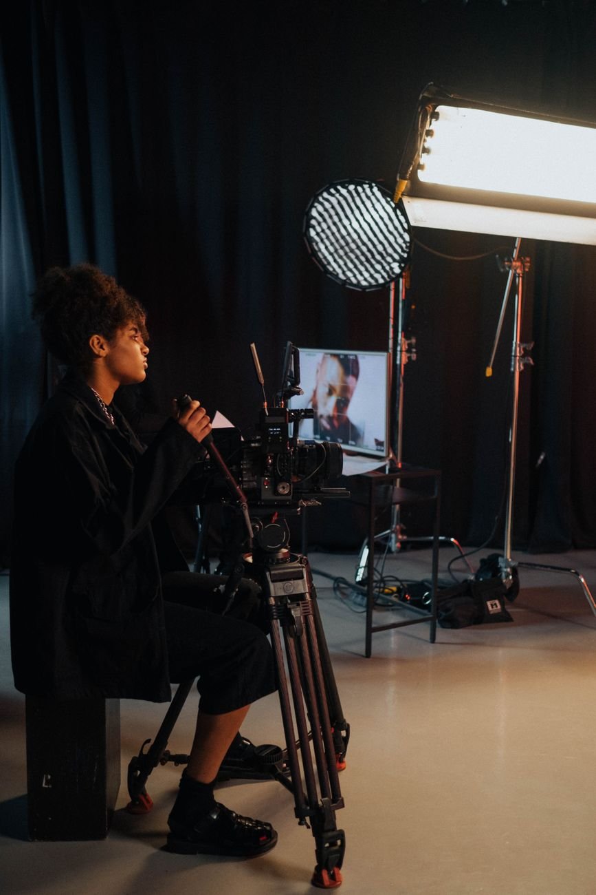 Videographer in dark studio at camera — the Bella Creates production environment